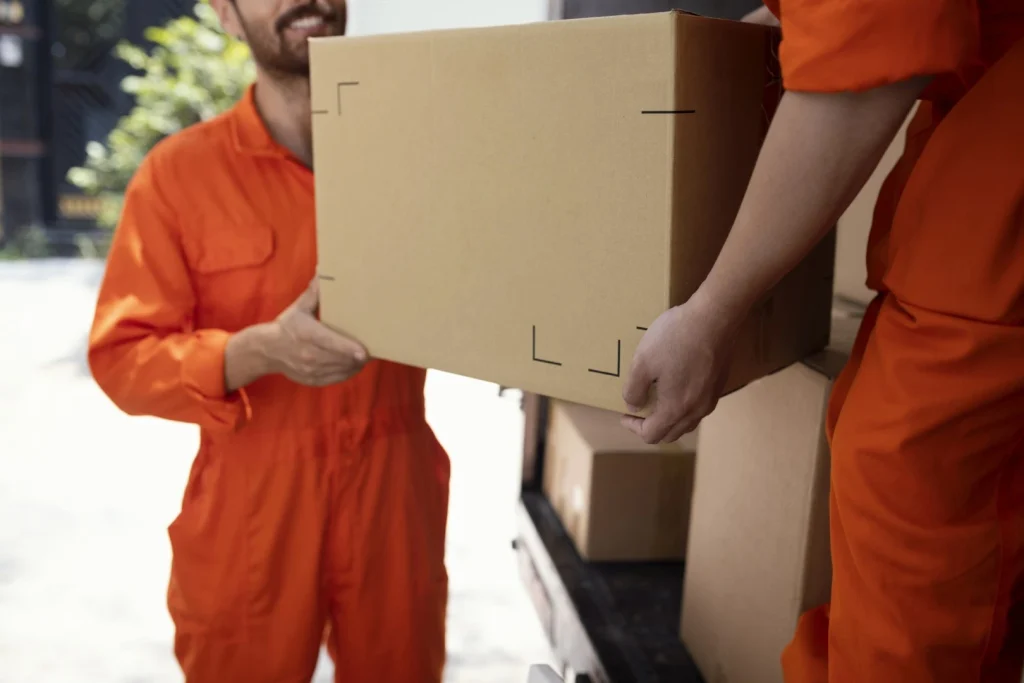 Servicio de fletes y mudanzas; Hombres vestidos de naranja descargando camión de mudanza