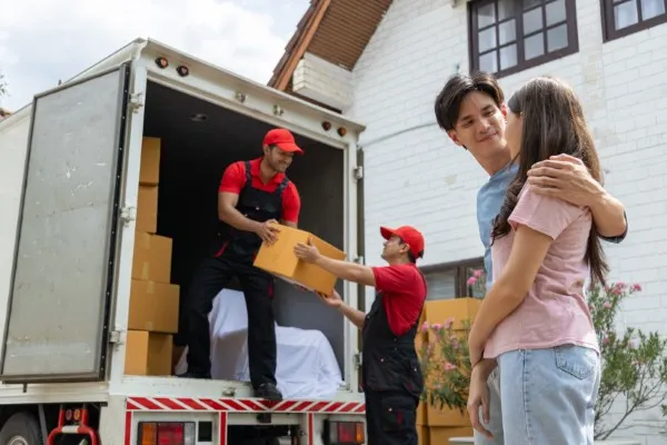 Una pareja feliz frente al camión de mudanzas foráneas que les lleva a su nuevo hogar.