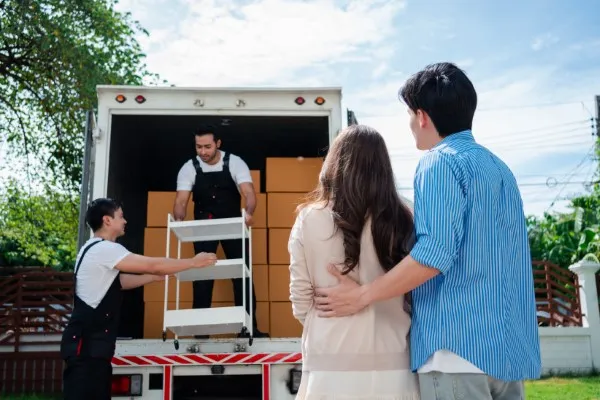 Pareja observando a los trabajadores descargar sus pertenencias durante sus mudanzas locales