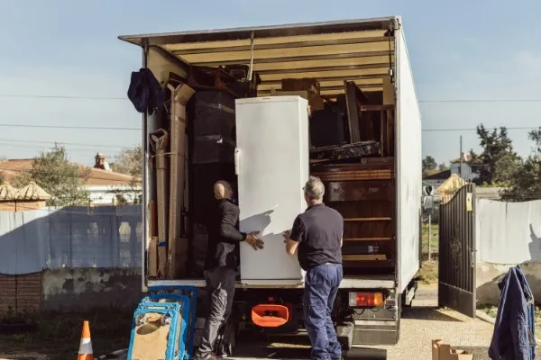 Dos hombres trasladan un refrigerador blanco en un camión durante un servicio de mudanzas foráneas.