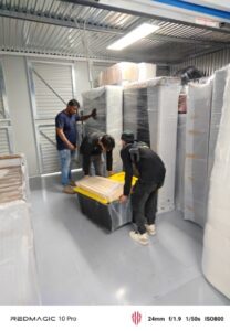 3 personas haciendo el empaque con playo de una caja organizadora por el costo de mudanzas.